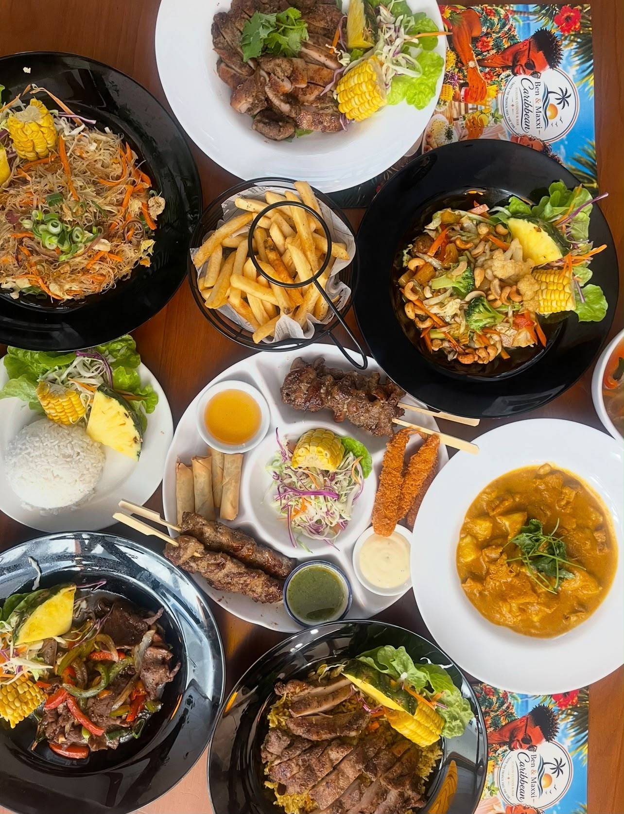 Overhead spread of Caribbean plates, skewers and curry